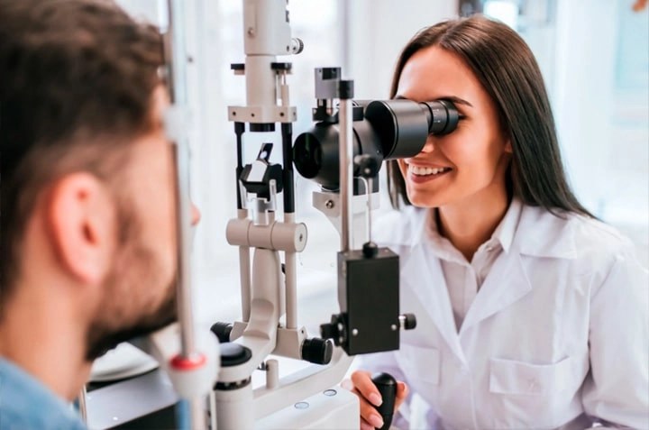 An optometrist examining a patient at the slit lamp