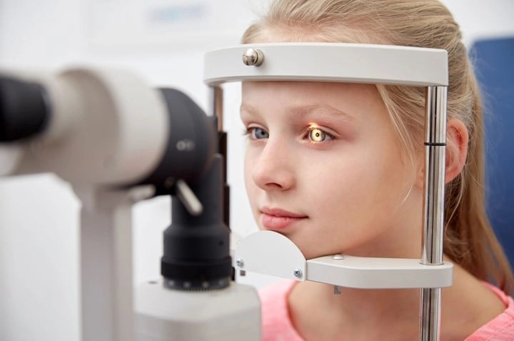A child having her eyes examined at the slit lamp